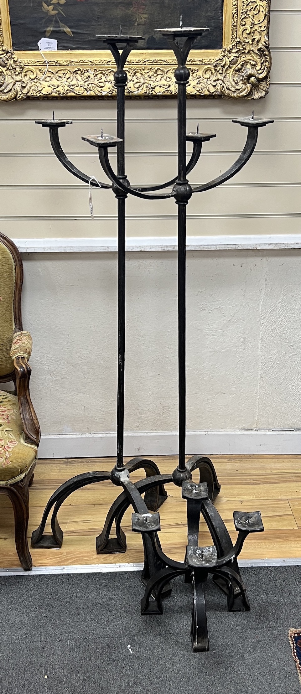 A pair of wrought iron three branch tripod pricket candlestands, height 146cm together with a matching four branch pricket candle holder